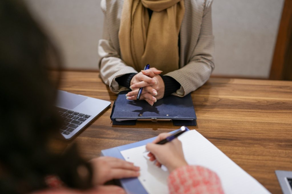 a woman sitting at a table with a laptop and a notebook