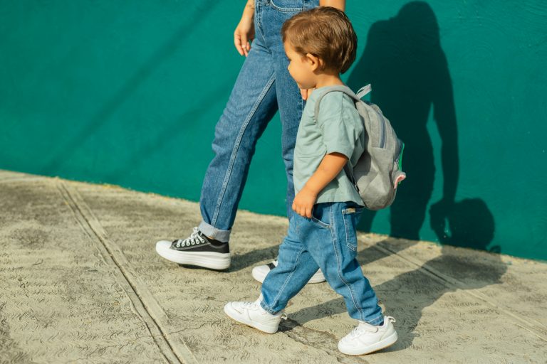 a child walking next to a person's legs