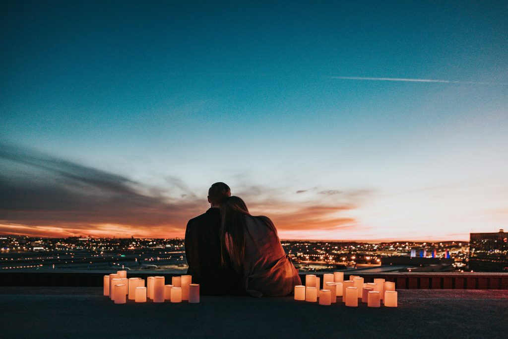 a couple sitting on a ledge with candles in front of them