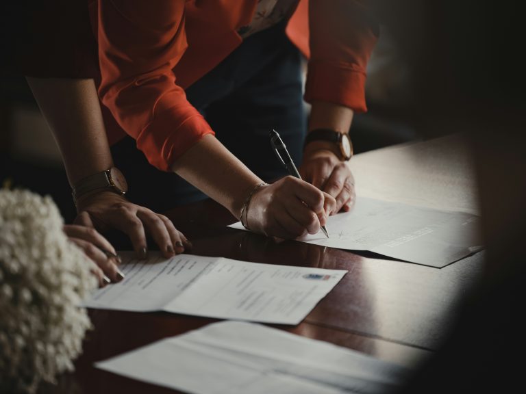 a person signing papers on a table