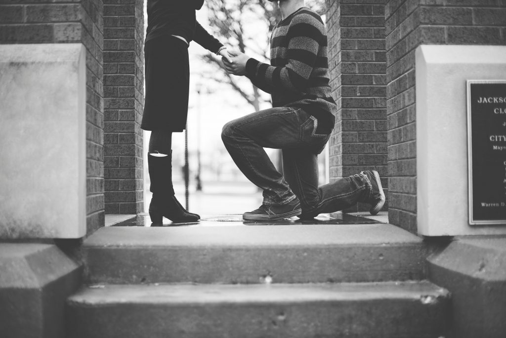 a man kneeling down holding a woman's hand